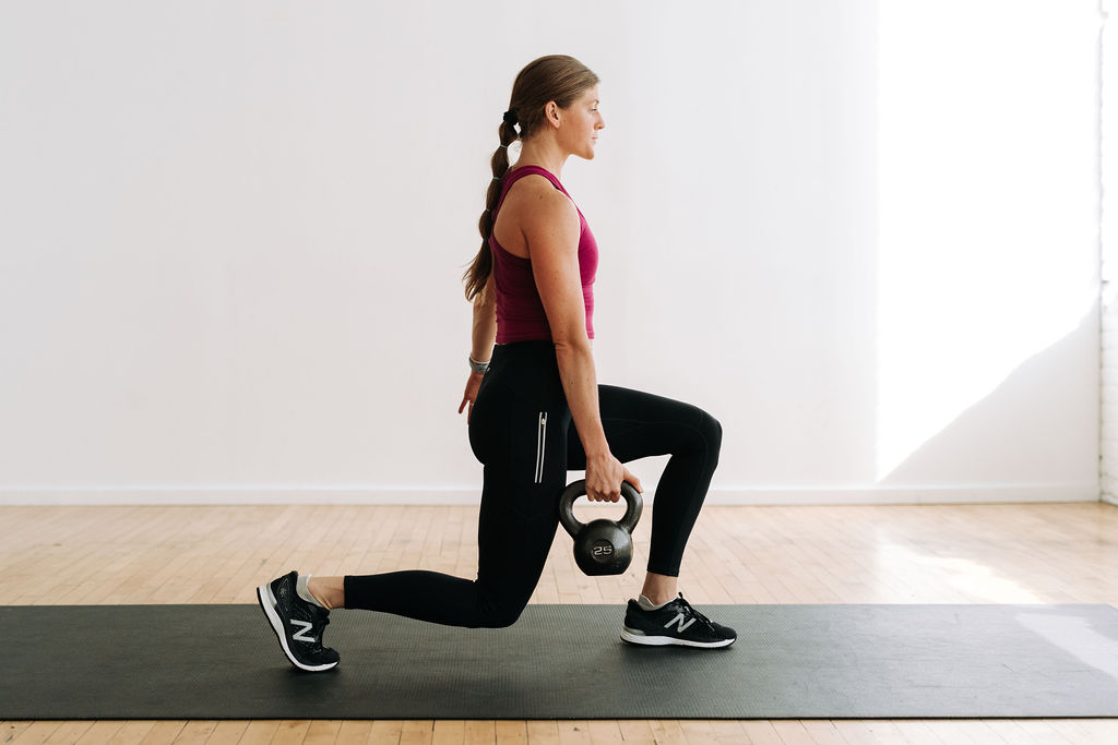 woman performing a split lunge with a kettlebell as part of the best kettlebell HIIT exercises at home