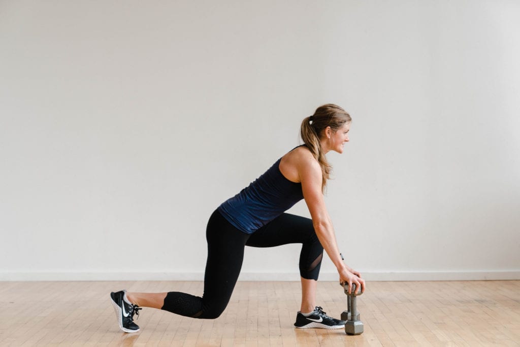 woman performing a lunge with dumbbells in a 30 minute leg workout at home