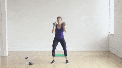 woman performing a squat and side leg lift with resistance band in a lower body workout