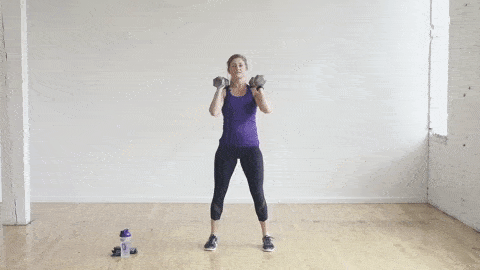 woman performing a front rack squat with dumbbells in a leg workout at home