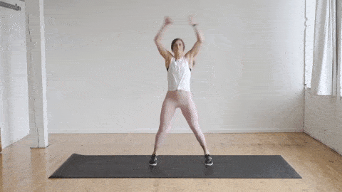 woman performing jumping jacks as part of a warm up