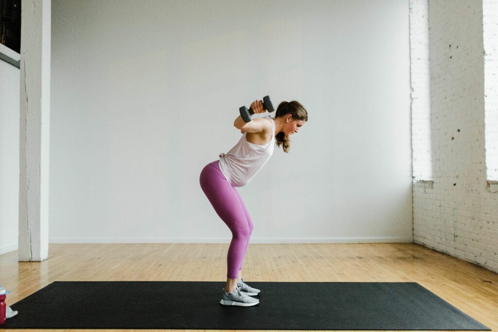 woman performing a dumbbell lateral raise in an arm workout with weights