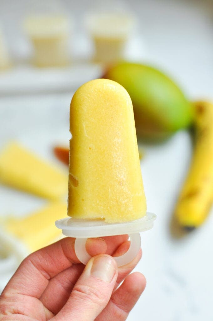 woman holding a mango fruit popsicle for kids