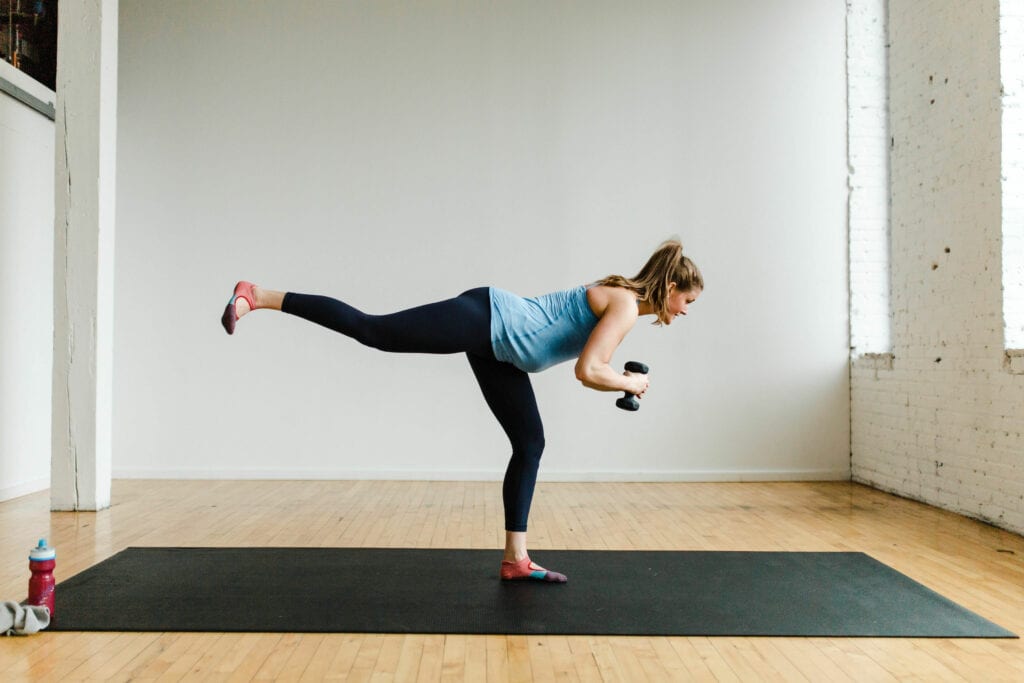 pregnant woman performing a rear leg lift in a barre class workout at home