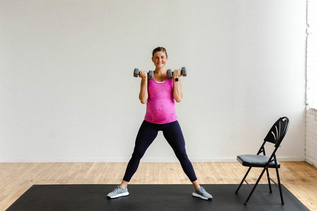 pregnant woman performing a dumbbell bicep curl in a pregnancy workout
