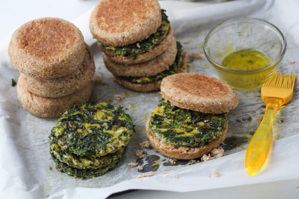 several spinach and egg breakfast sandwiches on a baking sheet