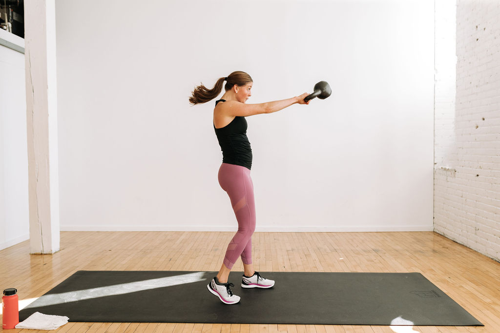 woman performing a kettlebell swing in a kettlebell workout at home