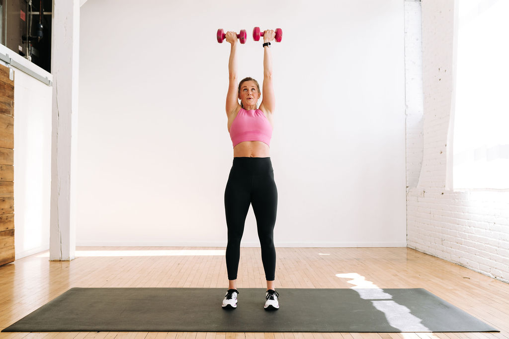 woman performing an overhead dumbbell press | full body workout at home