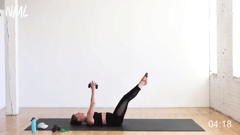 woman performing an alternating chest fly and leg lower in a barre core workout