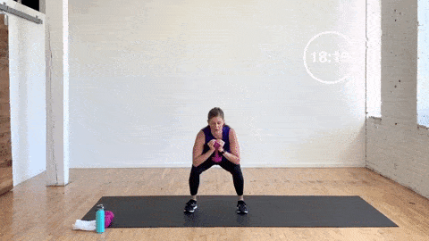 woman performing goblet squat jumps in a leg workout at home