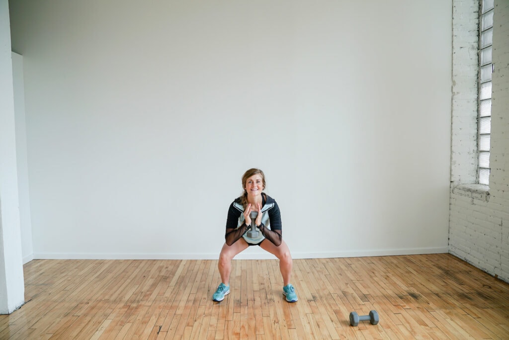 woman performing a dumbbell goblet squat in a lower body dumbbell workout