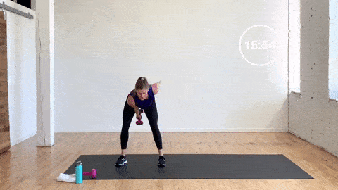woman performing a dumbbell swing and lateral hop in a lower body workout with dumbbells