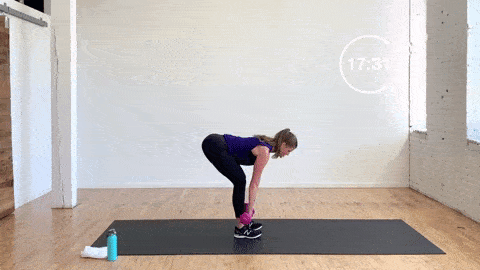 woman performing straight leg deadlifts with dumbbells in a leg day workout