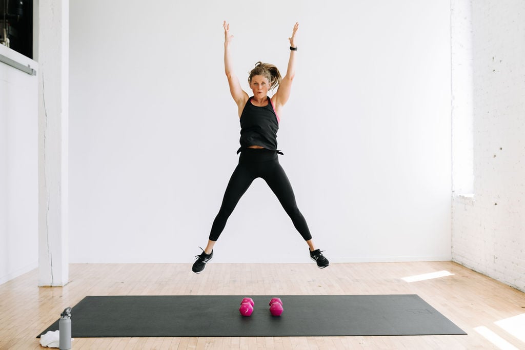 woman performing a squat jump ina HIIT workout at home
