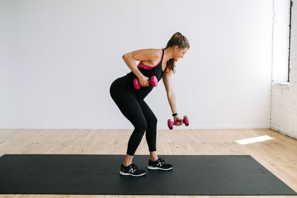 woman performing alternating back rows with dumbbells in a full body hiit workout with weights