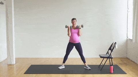 pregnant woman performing a 2-pulse sumo squat and half bicep curl with dumbbells