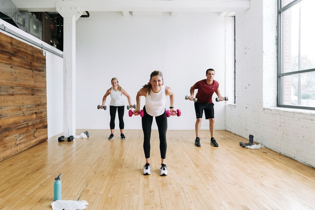 three people performing a bent over back row with dumbbells in a circuit training workout