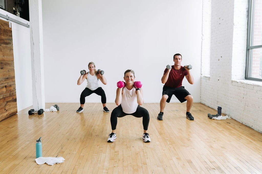 three people performing a dumbbell squat in a full body circuit workout