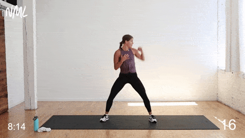woman performing sumo squat punches in a cardio kickboxing workout