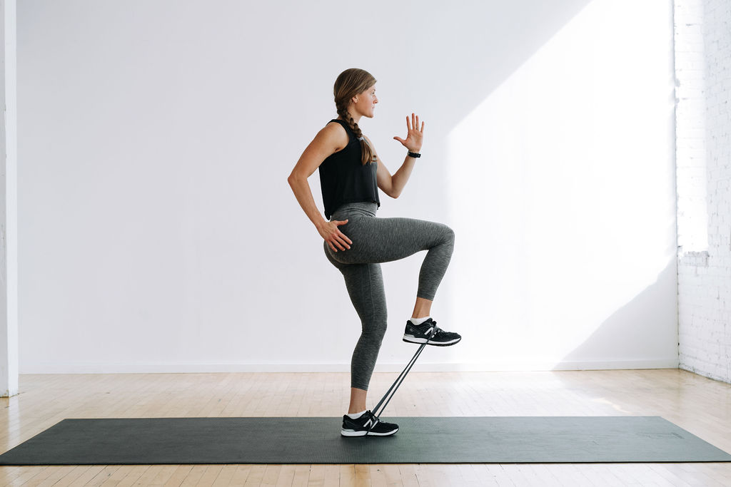 woman performing a banded knee drive as part of a glute activation warm up routine