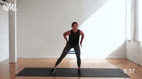 woman performing a banded single leg abduction as part of the best glute activation exercises