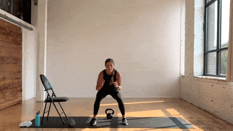 woman performing a kettlebell deadlift and front to back hop in a kettlebell leg workout