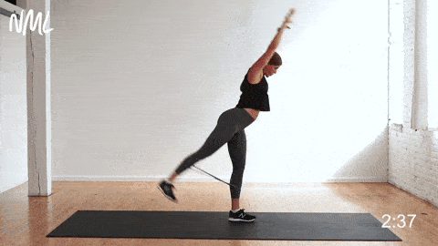 woman performing banded kickbacks or glute kick backs for glute activation at home