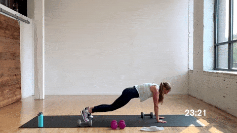 woman performing a push up dumbbell pass in a free weight workout