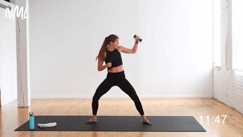 woman performing a sumo squat with high to low punches in a cardio kickboxing barre workout