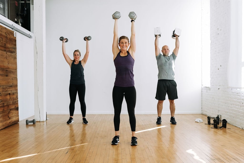 three people performing a push press exercise with dumbbells in a full body circuit workout
