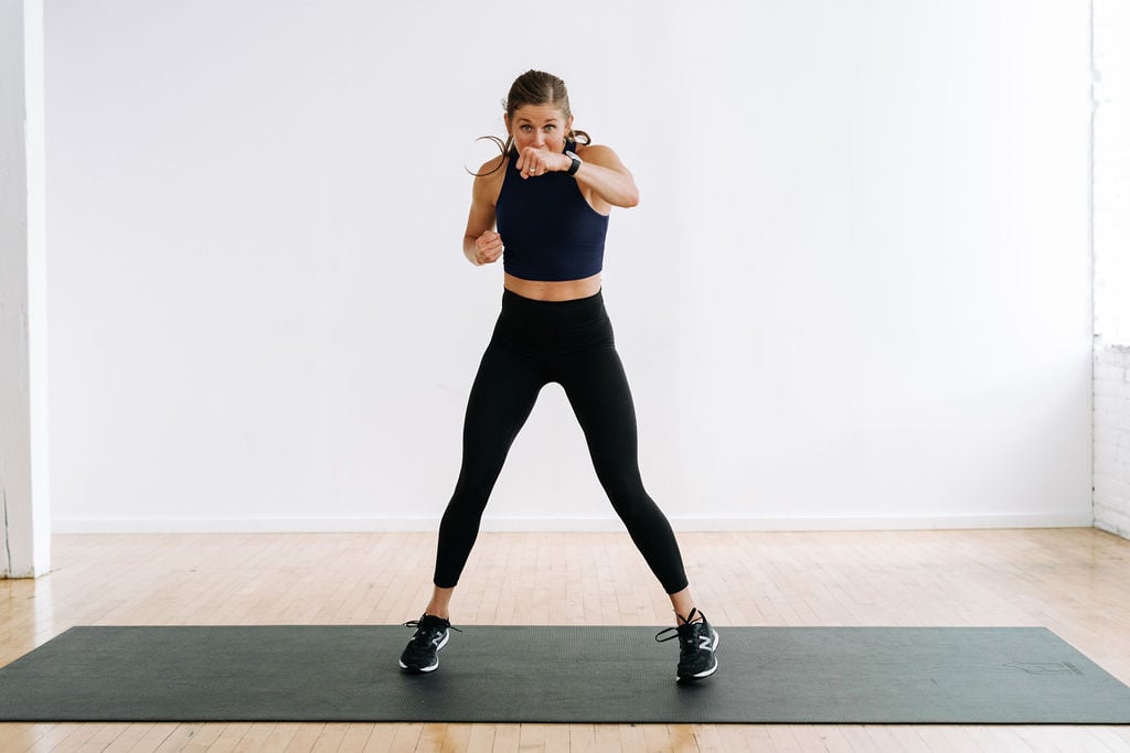 woman performing punch jacks in a high impact cardio workout