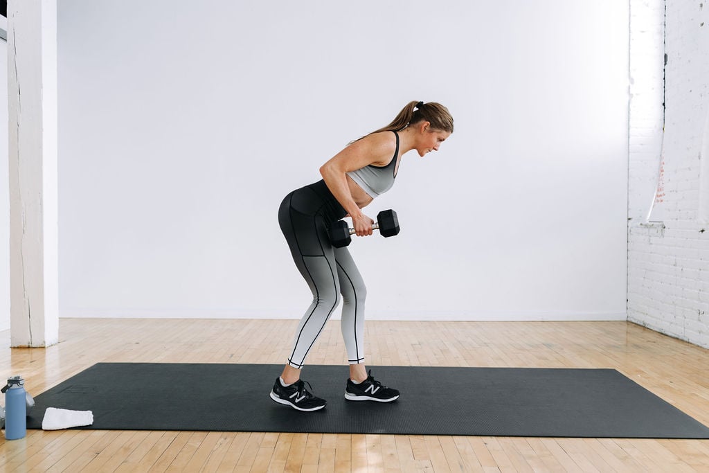 woman performing a single arm dumbbell back row in a legs and back workout