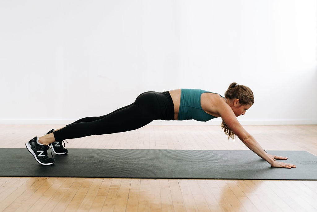 woman performing a plank walk out in a 5-minute ab workout at home