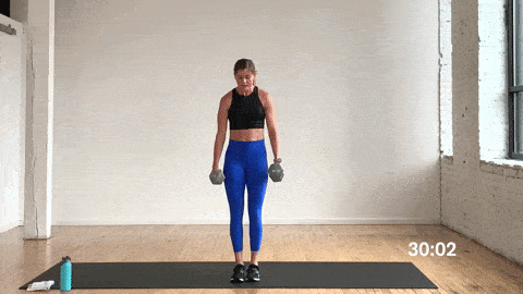 woman performing an alternating reverse lunge and bicep curl in a full body workout at home