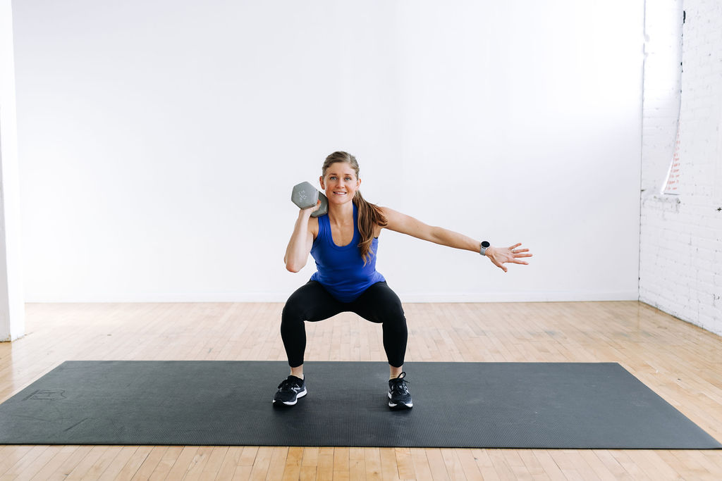 woman performing a unilateral dumbbell squat hold in a beginner HIIT workout