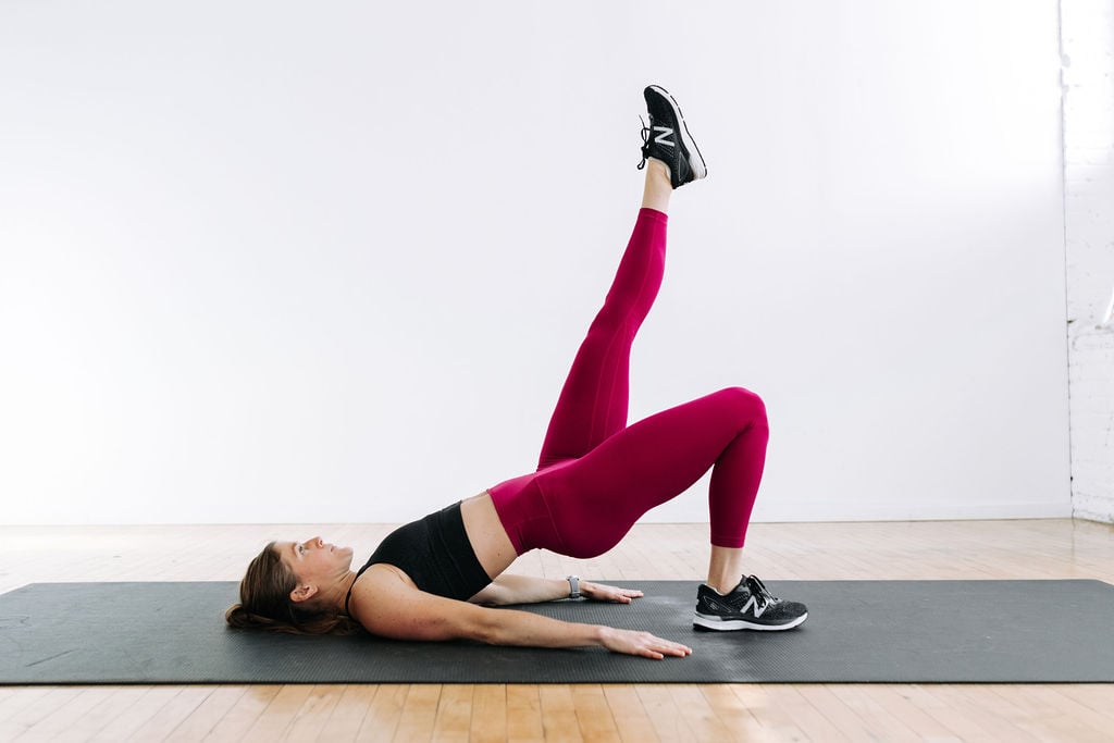 Woman performing a single leg glute bridge during a butt and thigh workout