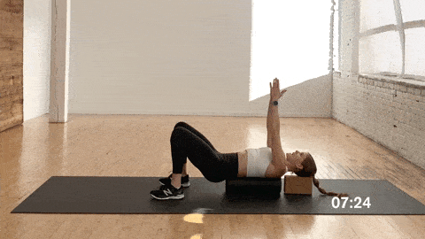 woman performing a chest opener stretch on a foam roller as part of the best foam roller exercises