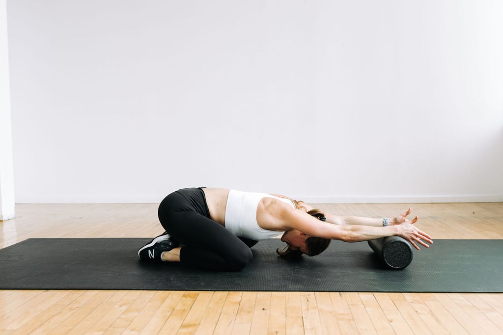 woman performing an upper body stretch on a foam roller as part of a home foam roll routine