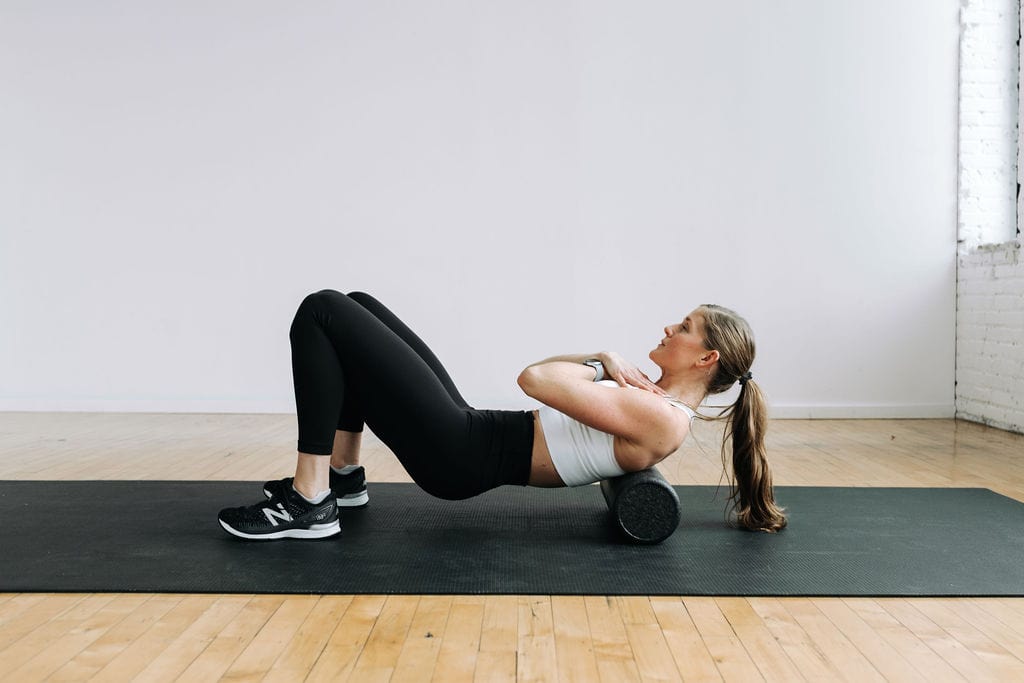 woman foam rolling her back as part of the best foam roller exercises to improve mobility and decrease muscle soreness