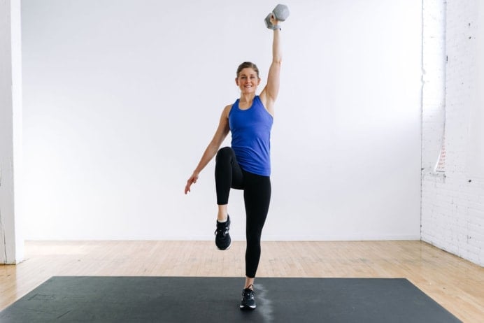 Low Impact HIIT Workout - woman performing a knee drive and overhead press with a dumbbell