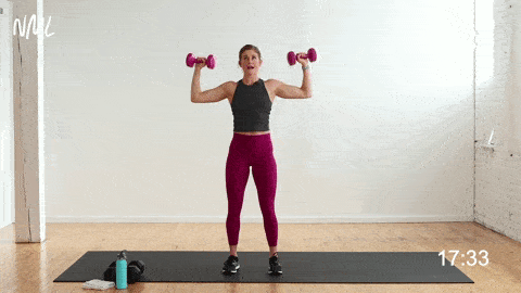 woman performing an overhead shoulder press with dumbbells in an upper body push workout
