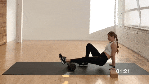 woman foam rolling her calf muscle as part of a stretch routine