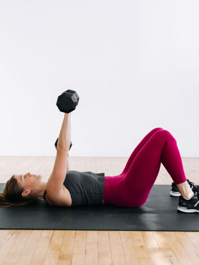 woman performing a dumbbell chest press in a push workout at home