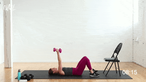 Woman performing Skull Crushers Tricep Exercise with dumbbells 