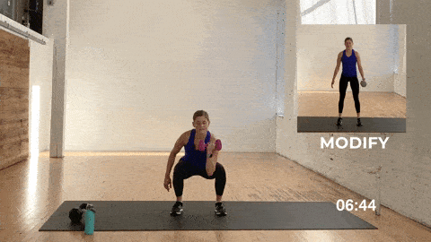 woman performing an uneven squat and rotational press in a total body HIIT workout at home