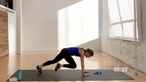 woman performing 3-count mountain climbers in a full body workout with a resistance band