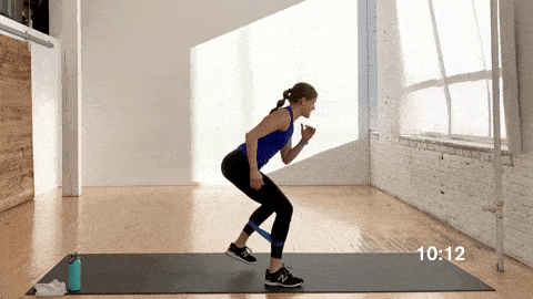 woman performing banded v-walks or banded monster walks and jumping jacks in a resistance band workout