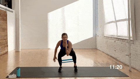 woman performing 80/20 change stance banded squats in a total body resistance band workout