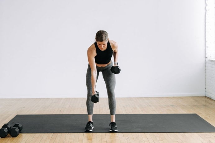 woman performing alternating back rows with dumbbells in a legs and back workout