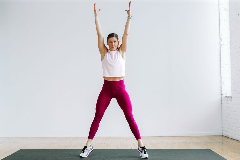 woman performing a sumo squat and reach in a beginner cardio workout at home